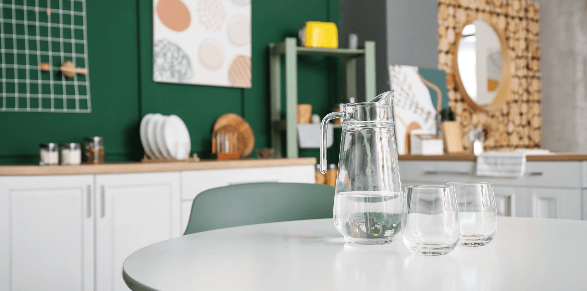 Glass pitcher and tumblers of filtered water on a bright kitchen table