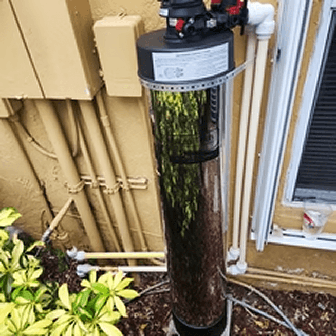 Point-of-use water filter mounted along a home's exterior plumbing